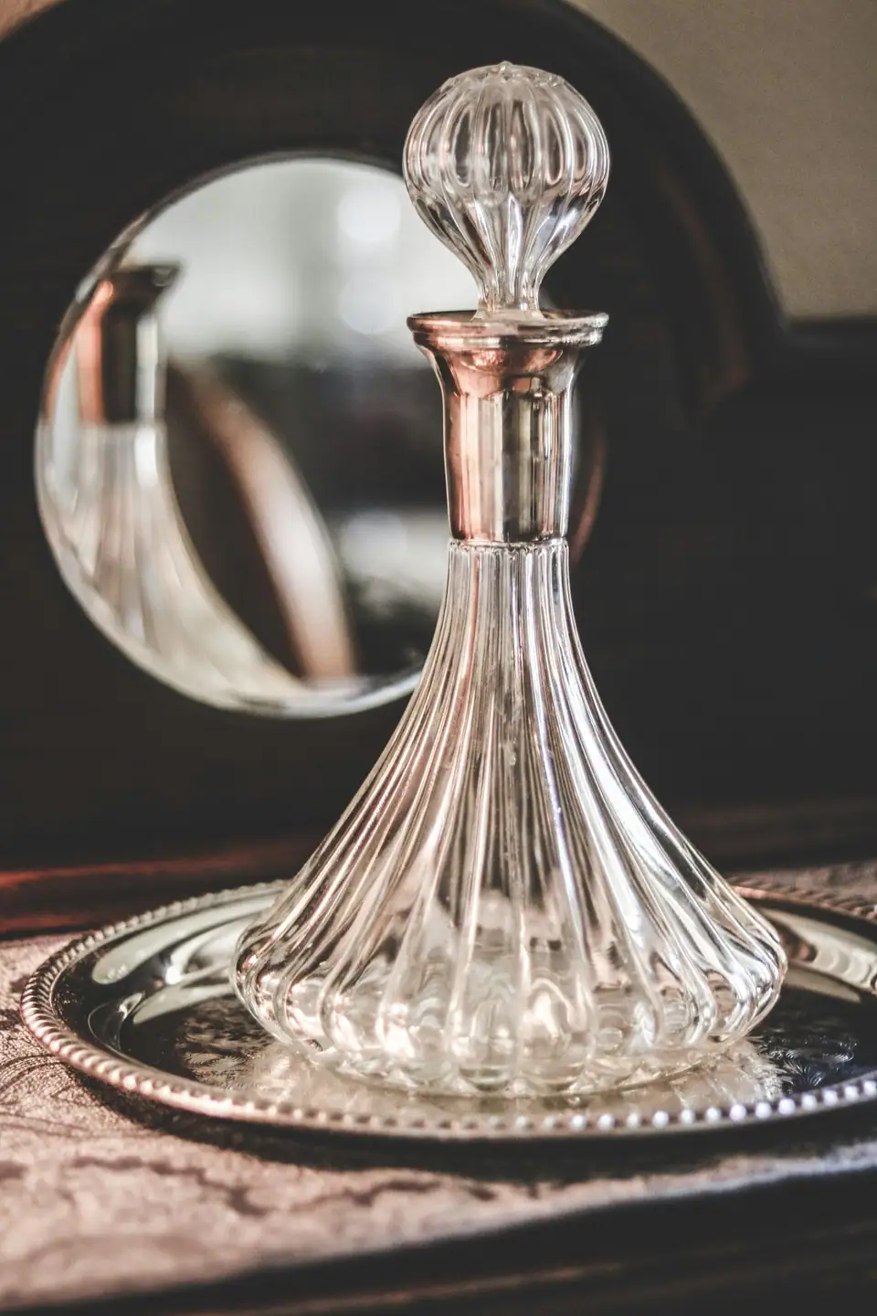 A ribbed crystal ship decanter with a stopper standing on a silver tray