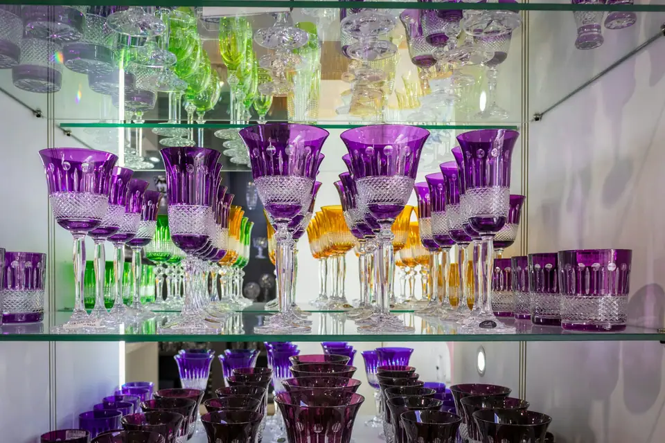 Shelves of cut crystal stemware in purple, amber and clear glass displayed in a glassworks shop