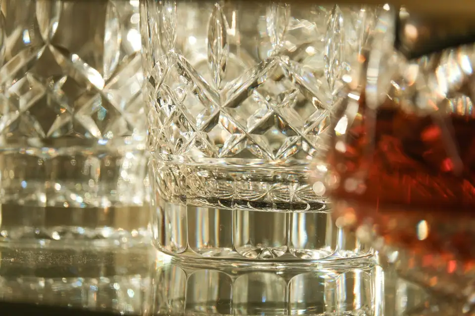 Macro close-up of cut crystal glasses with deep diamond facets catching warm light