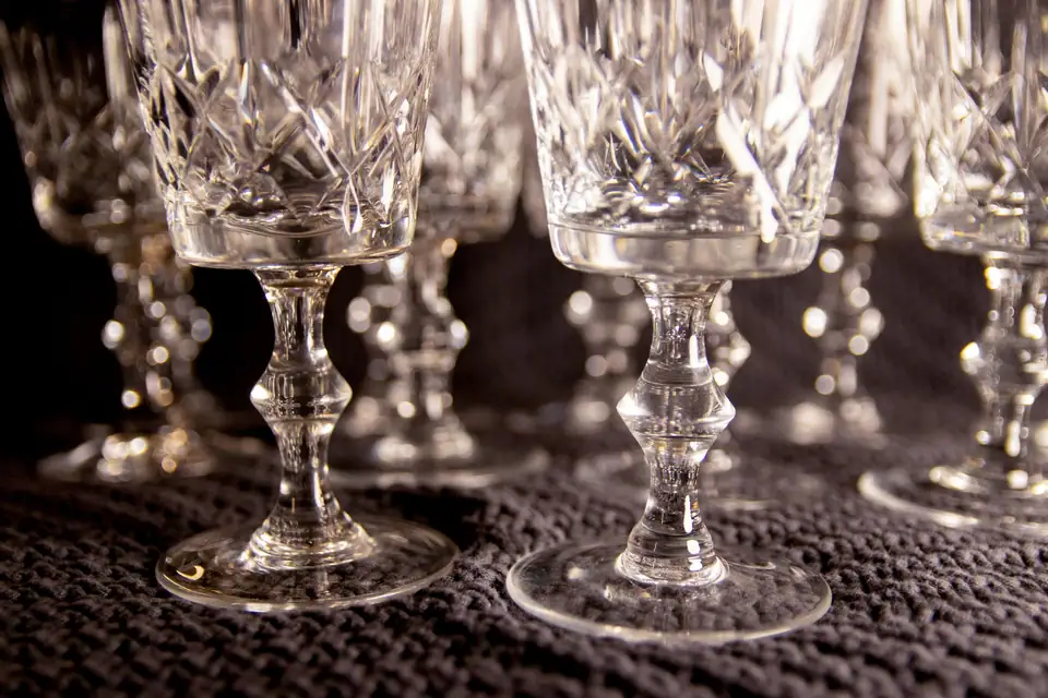 Cut crystal wine glasses with deep faceted patterns standing on a dark textured tablecloth
