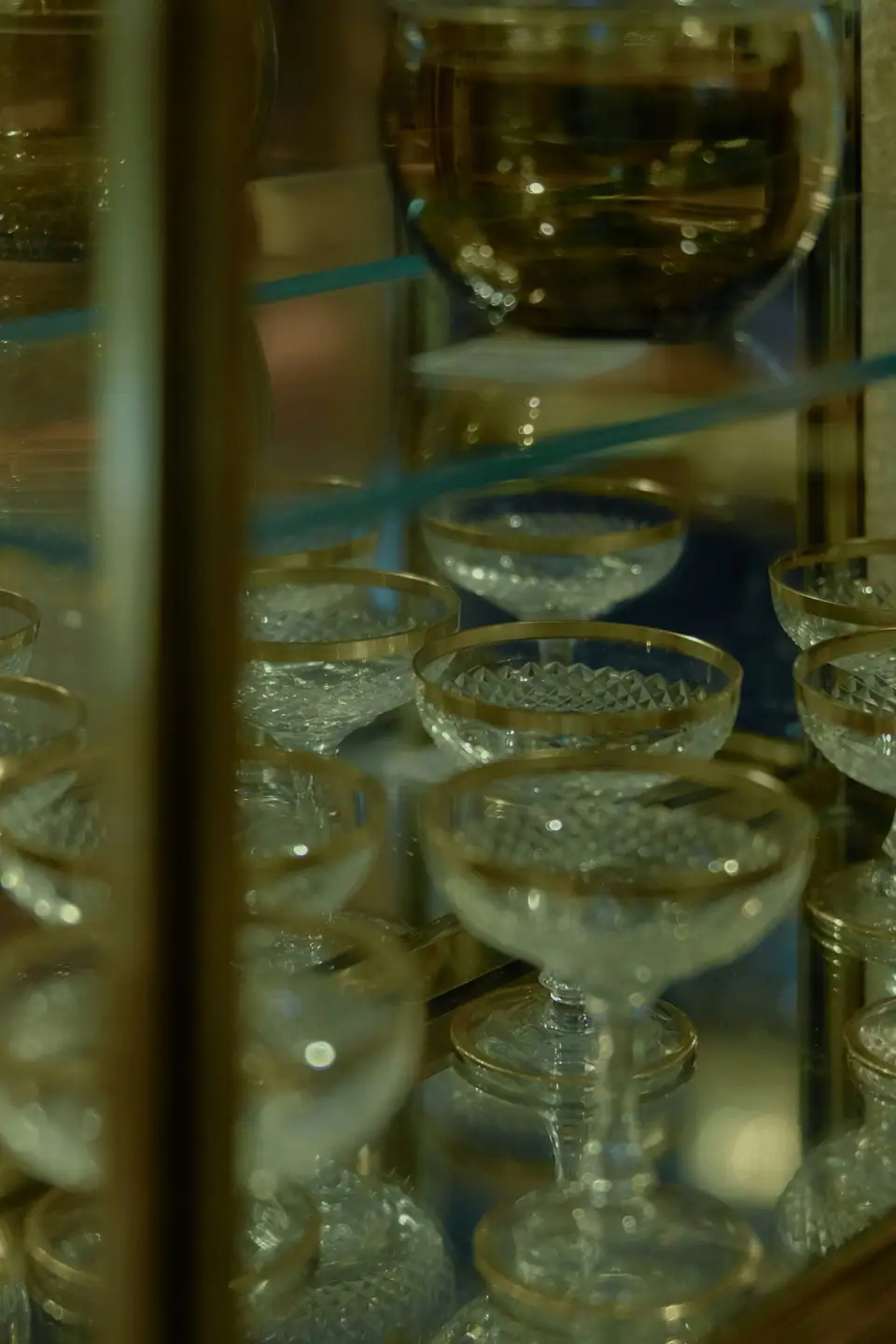 Crystal coupes with gold rims displayed in a glass cabinet